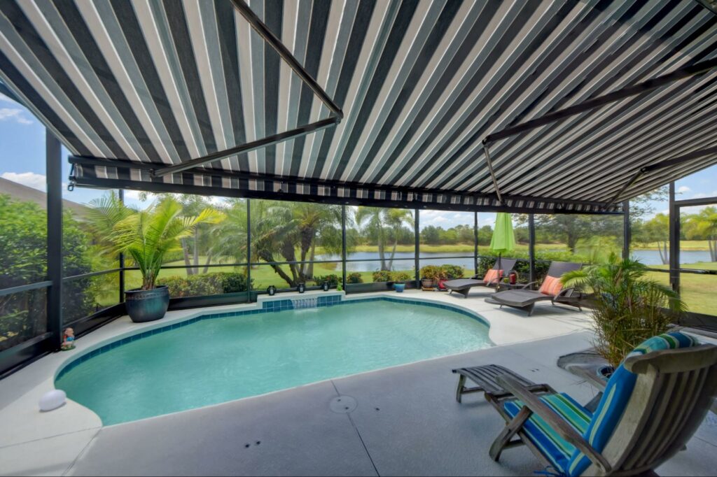 A beautiful enclosed pool area with blue striped motorized awning in sunny Orlando, Florida.