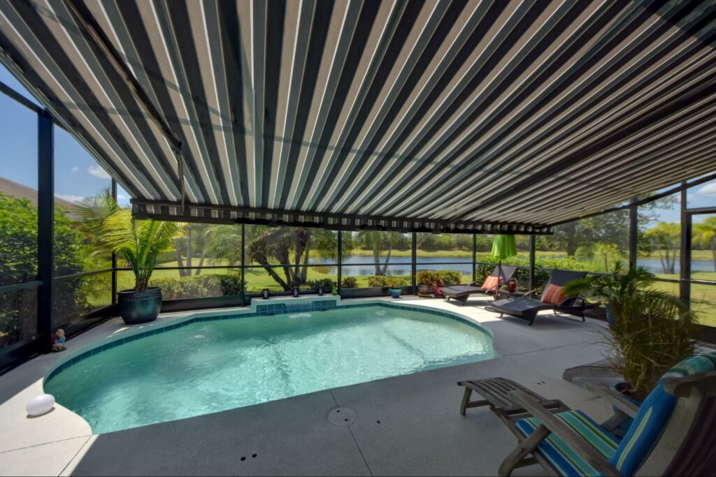 A beautiful poolside patio has protection from the hot sun with this blue striped motorized awning in sunny Florida. See your options here!