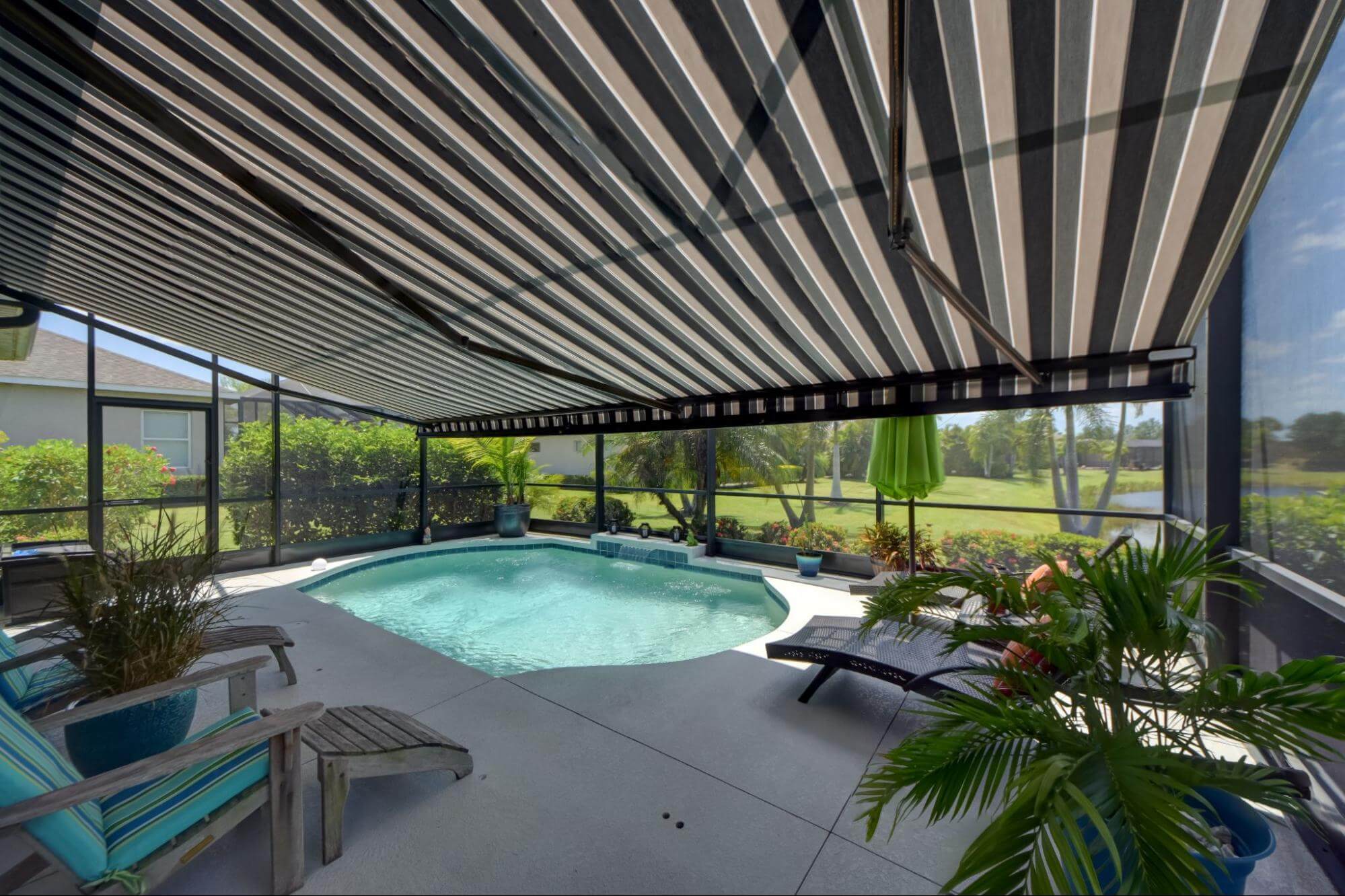 A North Naples patio and pool with a blue striped motorized awning. SPF is the premier provider of sun-blocking products for your home. Contact us for a free estimate today.