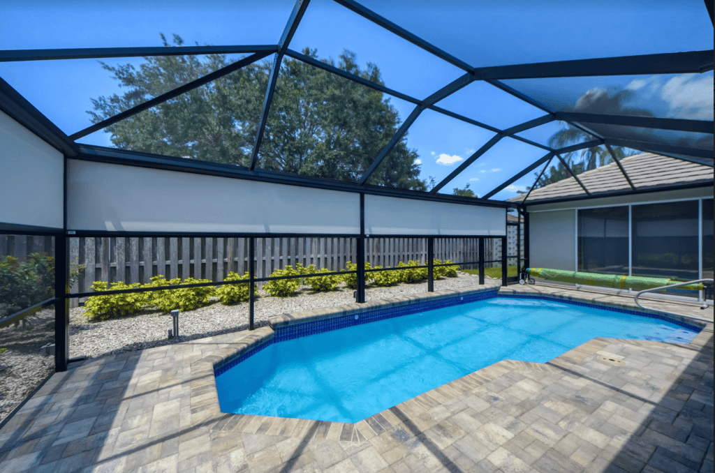 A family enjoys their pool-side patio that showcases three motorized retractable privacy screens to block the hot sun and insects and give seclusion for family dinners.