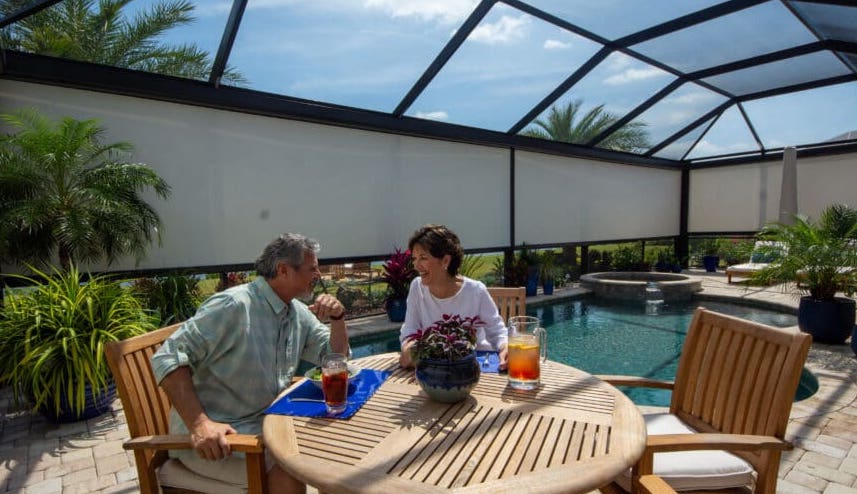 This Florida couple enjoys a private lunch on their poolside patio. They have selected motorized screens that offer complete seclusion when rolled down.| Sun Protection