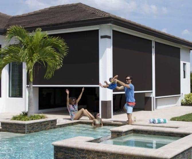 A Florida family plays in their pool. The poolside patio features three retractable privacy screens for when they need a break from the sun or some privacy.