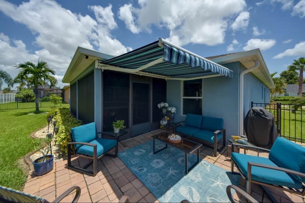 A blue striped awning extends over a patio with blue furniture.