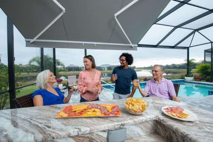 A group of four adults enjoy snacks on an outdoor patio under a retractable awning.