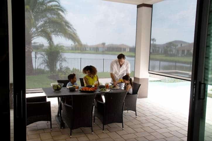 A family of four enjoy dinner on their shaded patio with retractable solar screens.